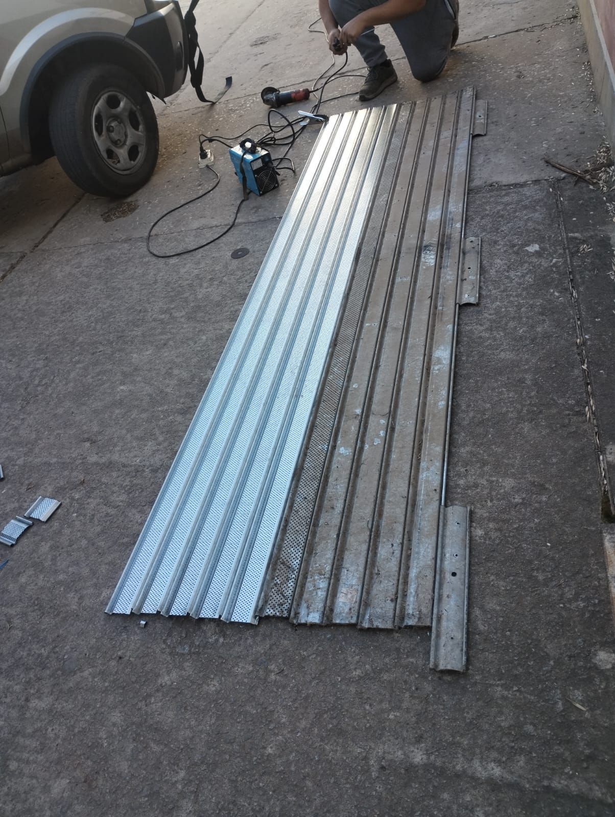 Un hombre está arrodillado junto a un gran trozo de metal.