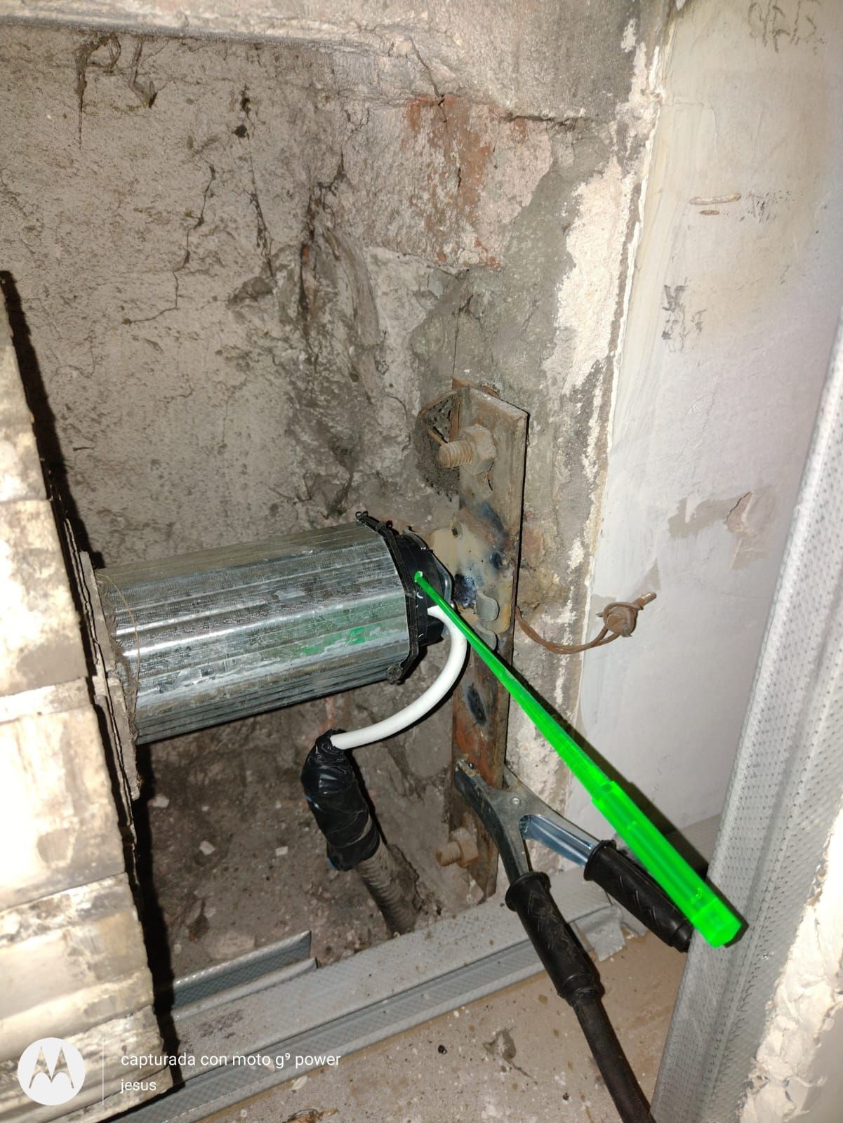 Se está utilizando un cepillo de dientes verde para quitar un trozo de metal de una pared.