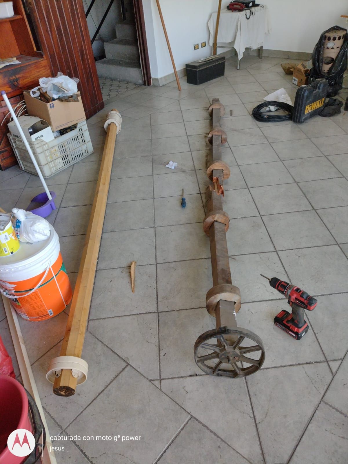 Un taladro está en el suelo al lado de un poste de madera.