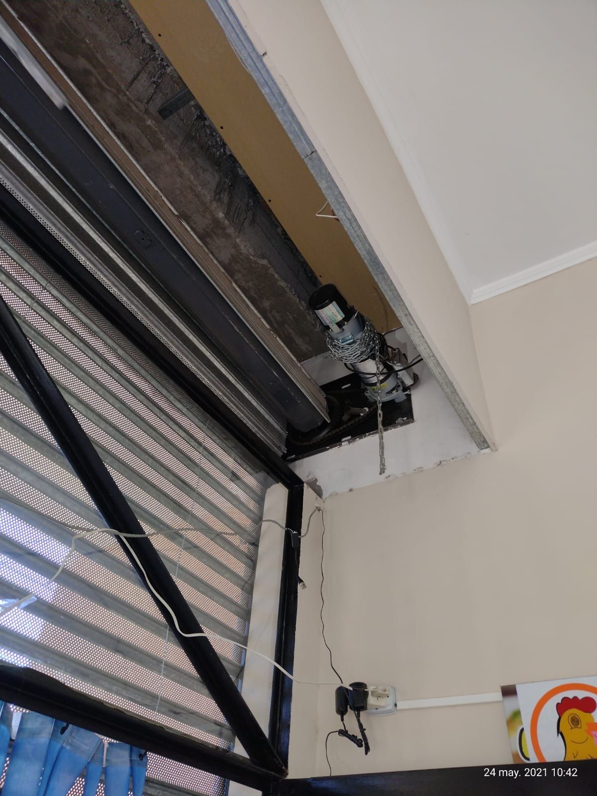 Un cartel con un pollo está al lado de una ventana.