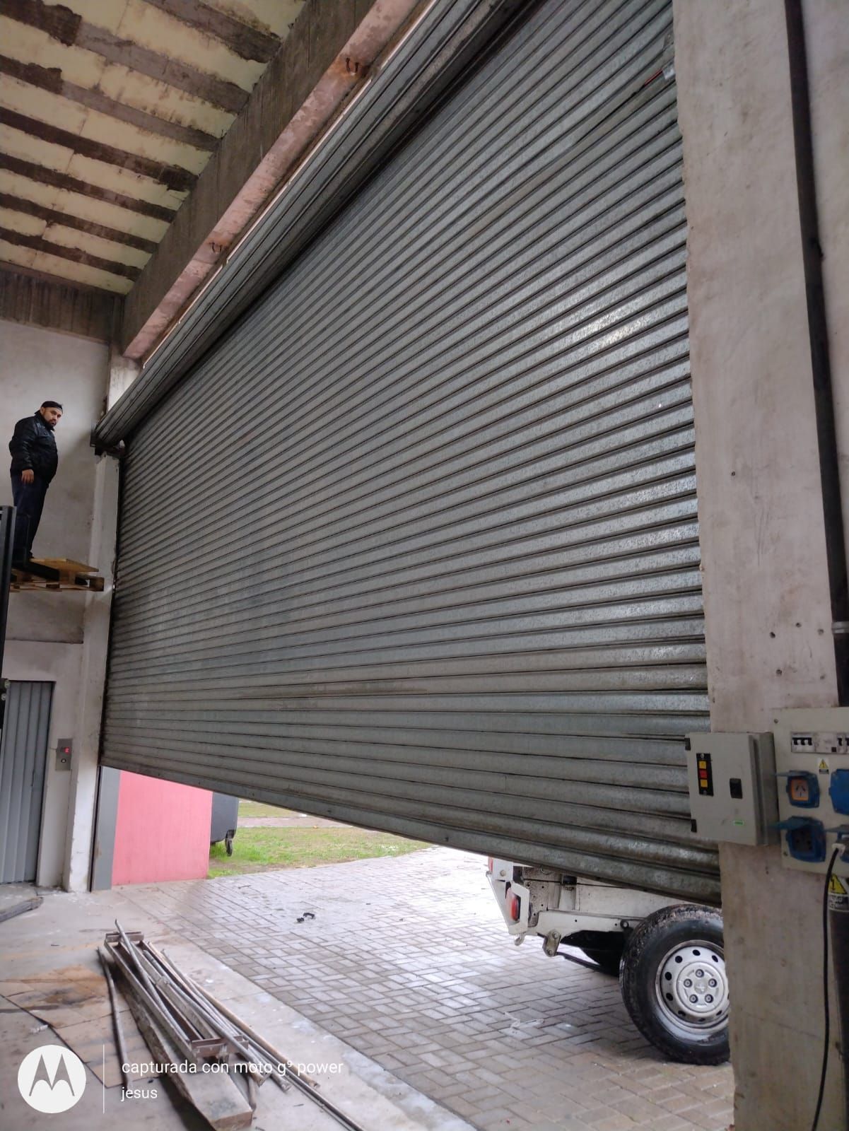 Un hombre está parado en la parte superior de un edificio al lado de una puerta de garaje.