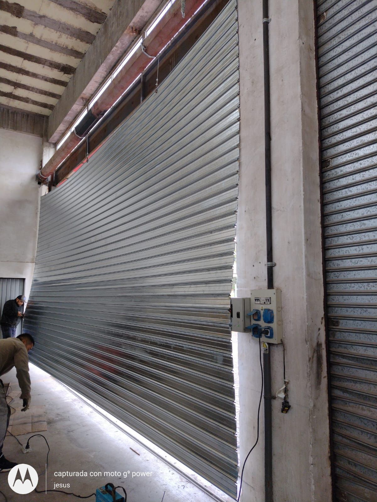 Un hombre está trabajando en una puerta de garaje en un edificio.