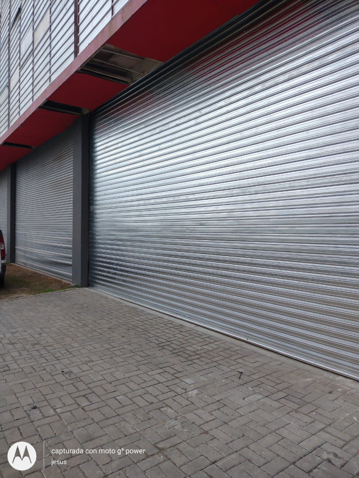 Un coche está aparcado delante de una gran puerta de garaje metálica.