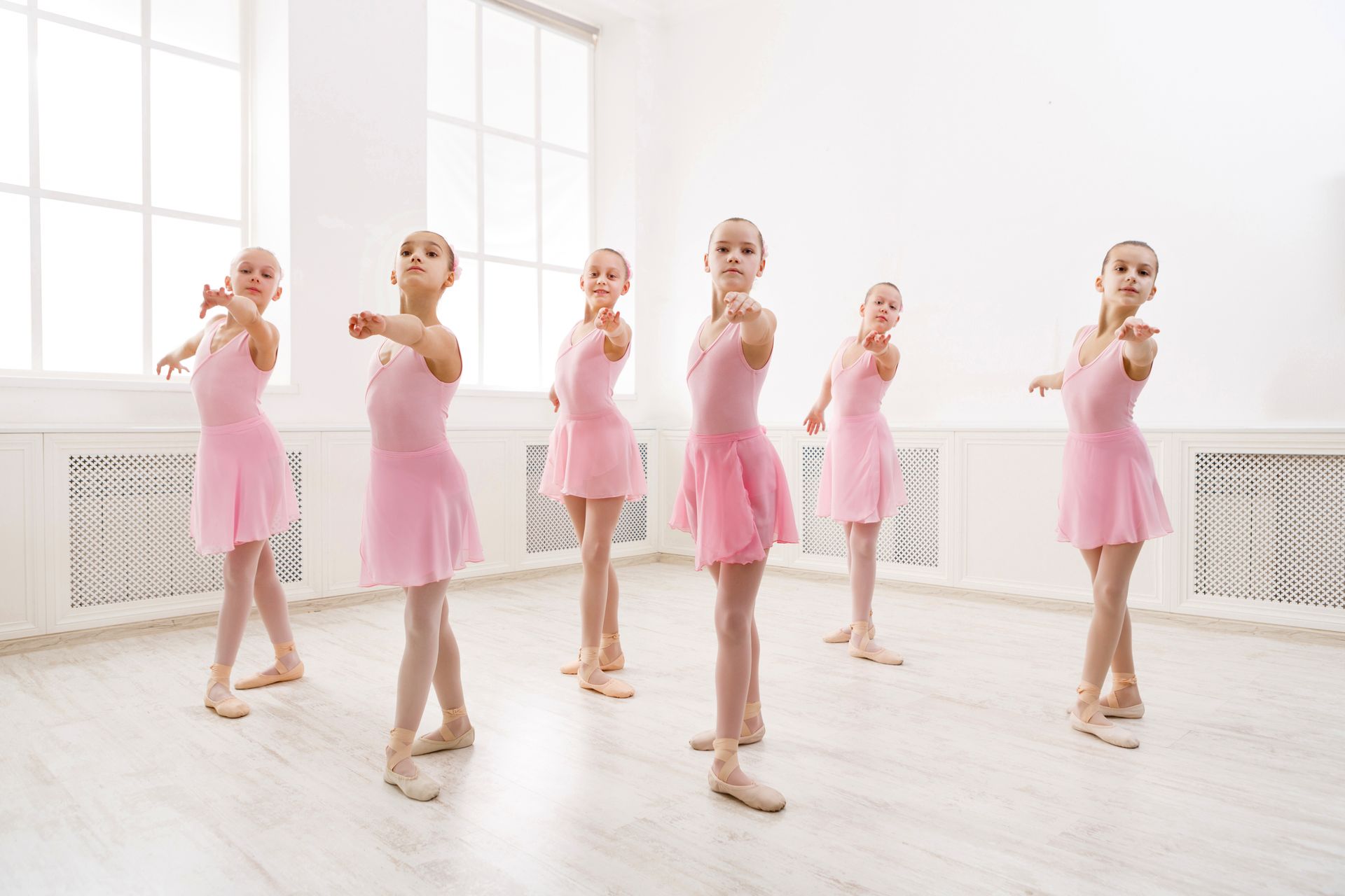 A group of young ballerinas are dancing in a dance studio.