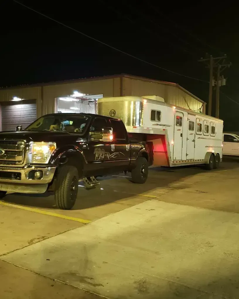 A truck is towing a trailer in a parking lot at night.