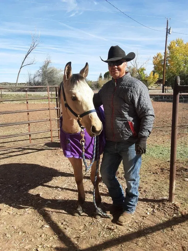 A man in a cowboy hat is standing next to a horse.