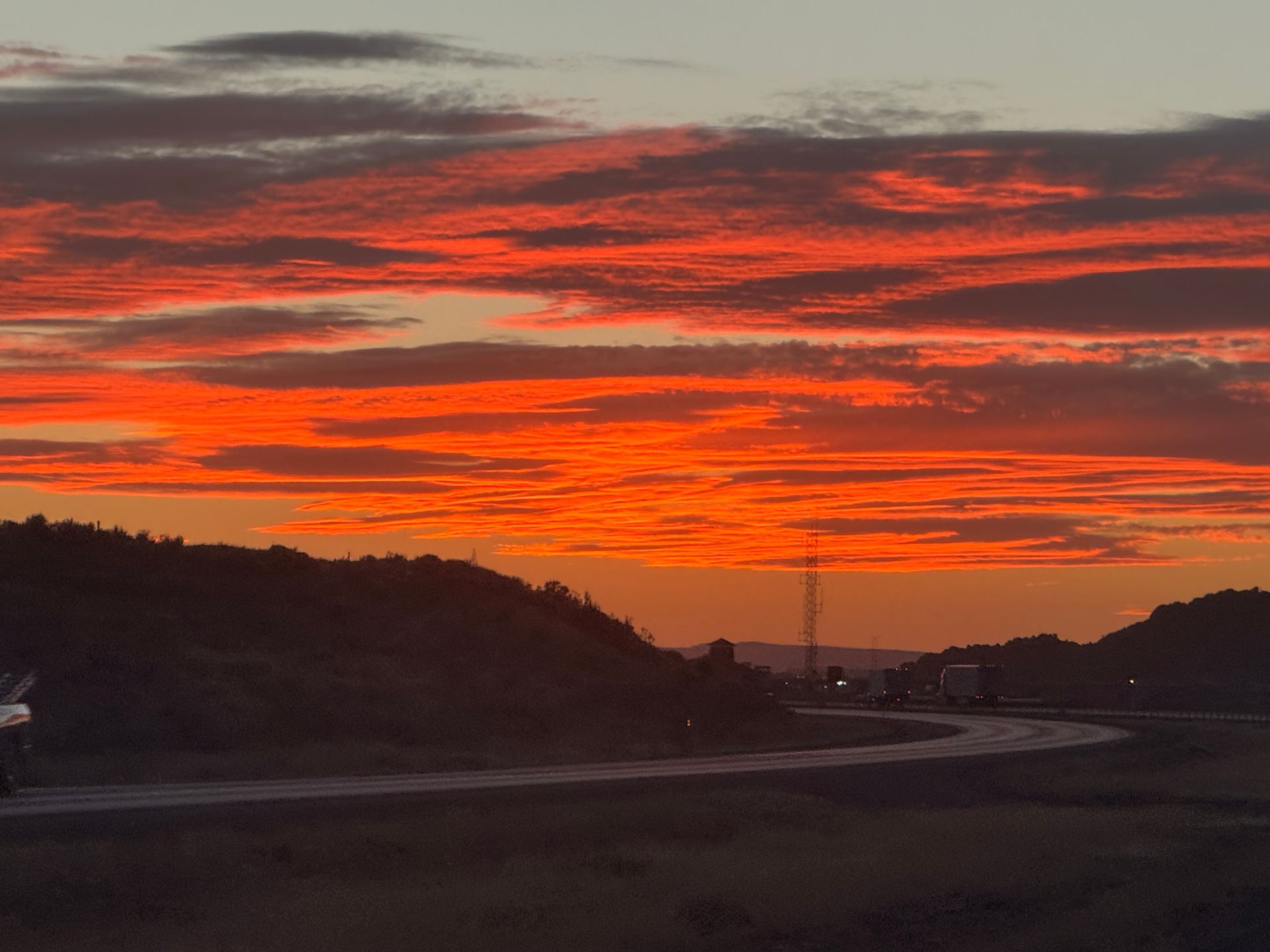 A sunset over a road with a lot of clouds
