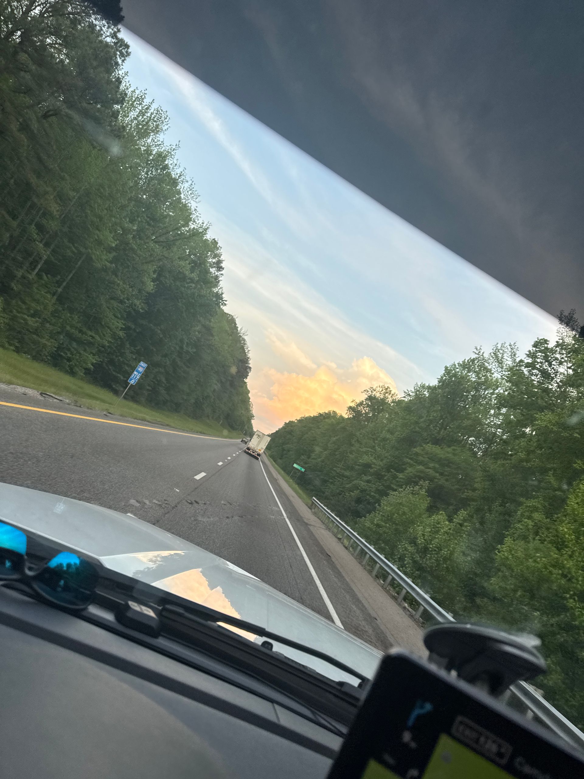 A car is driving down a highway with trees on both sides.