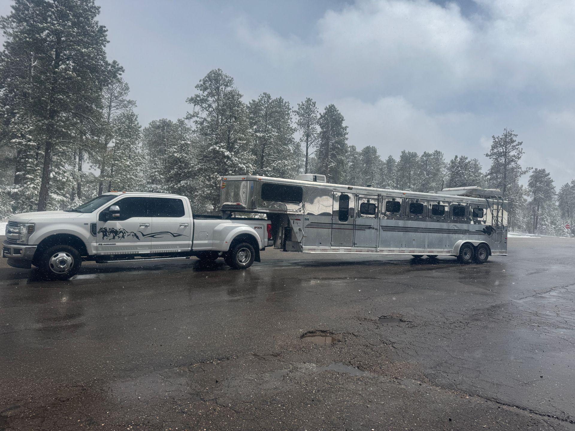 A white truck is pulling a trailer with a horse on it.