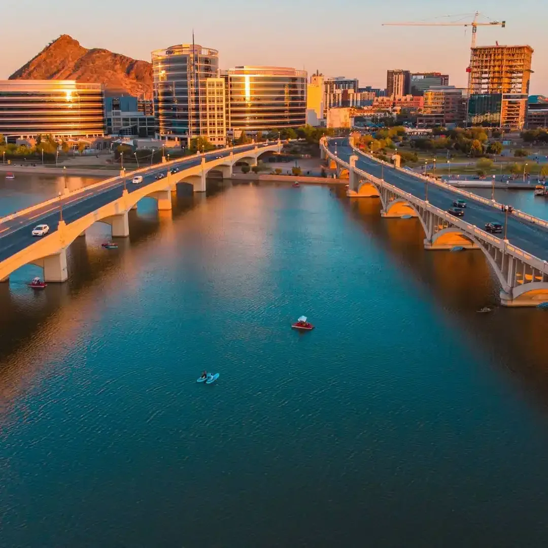 An aerial view of a bridge over a body of water with a city in the background.