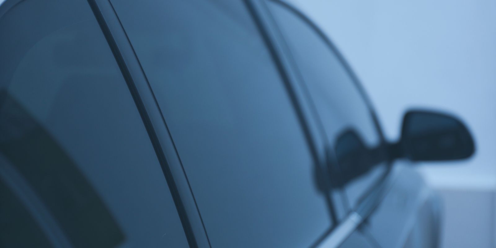 A close up of a car window with a reflection of a person in it.