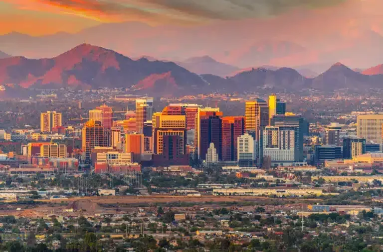 An aerial view of a city skyline with mountains in the background at sunset.
