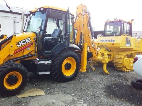 Yellow JCB backhoe and Komatsu bulldozer parked outdoors.