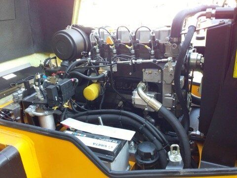 Engine of a yellow construction vehicle with black components, including a battery and filter.