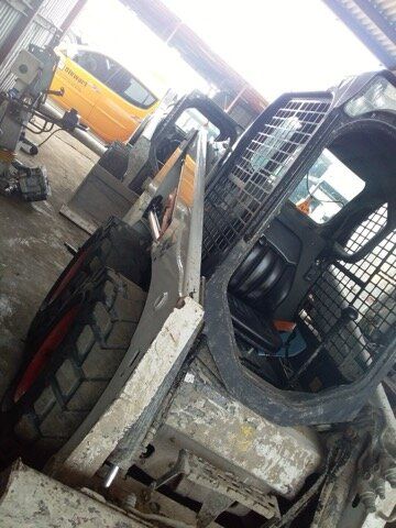 Skid steer loader inside a garage with other vehicles.