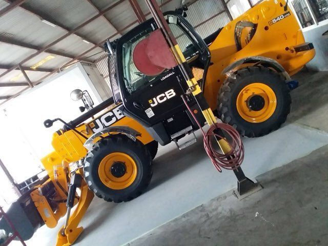 Yellow JCB telehandler in a garage.