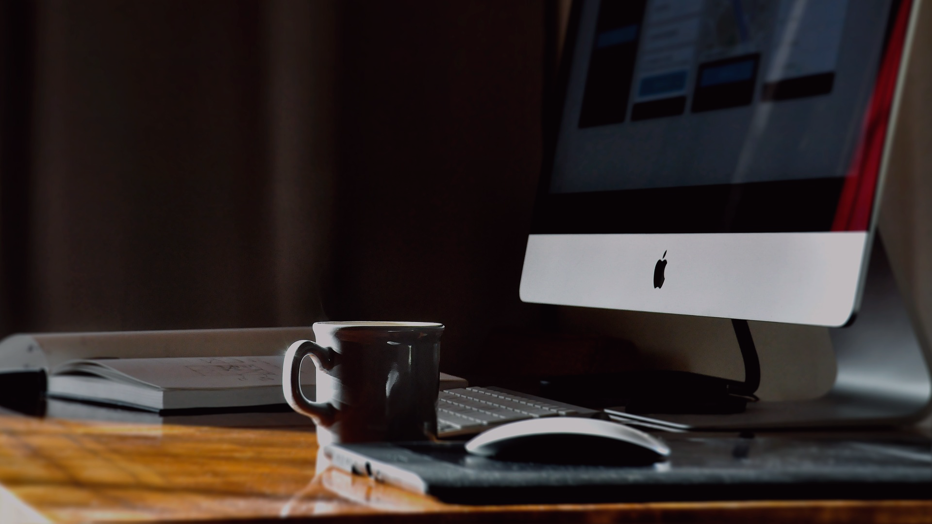 Desktop computer on a wooden desk with a coffee mug and mouse beside it.