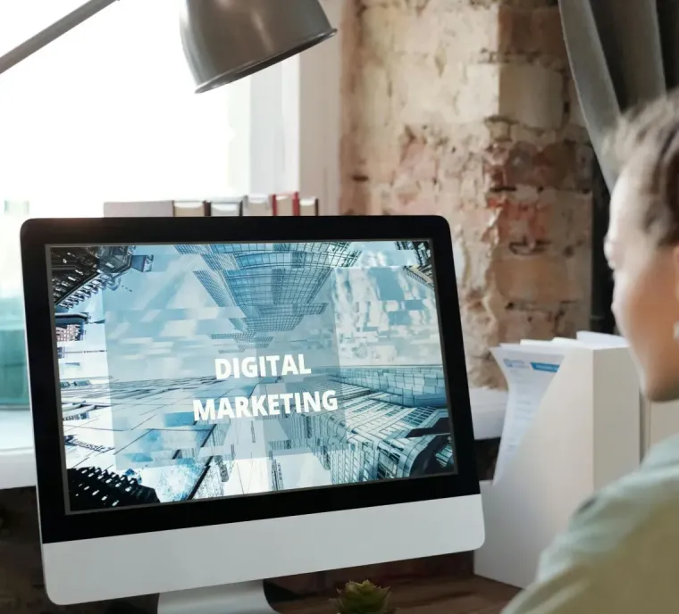 Person at desk viewing a monitor that says “Digital Marketing” in a bright office