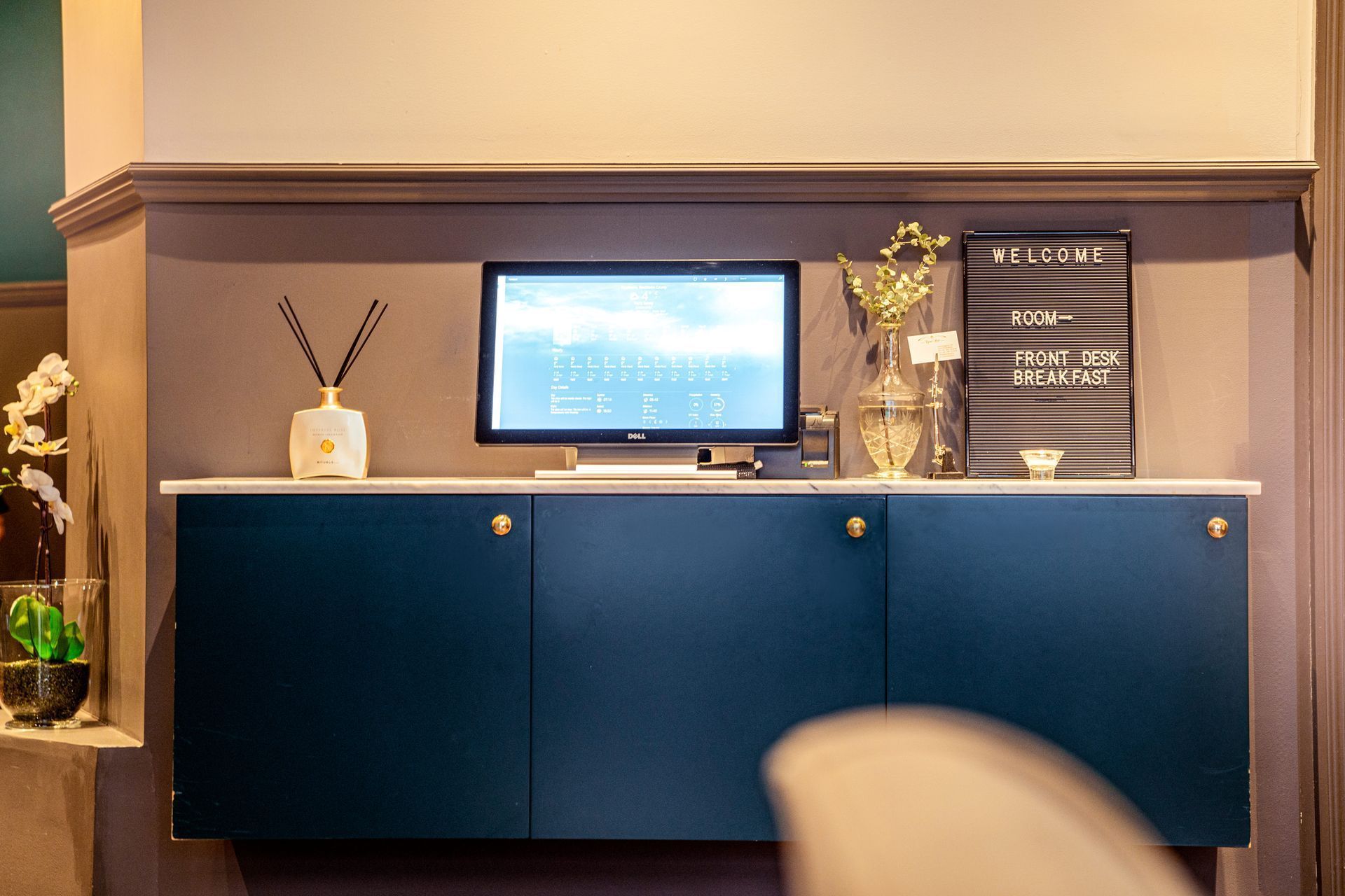 Blue office cabinet with a computer monitor, decor, and a framed sign on top against a beige wall.