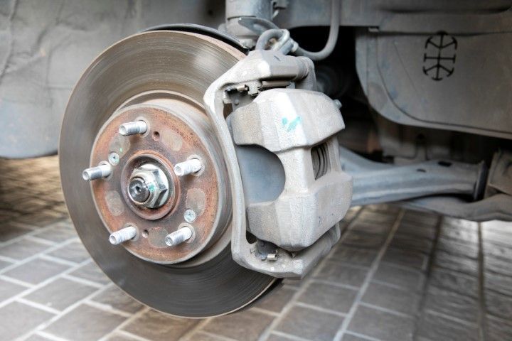 Car's brake assembly, showing a rotor, caliper, and lug nuts.