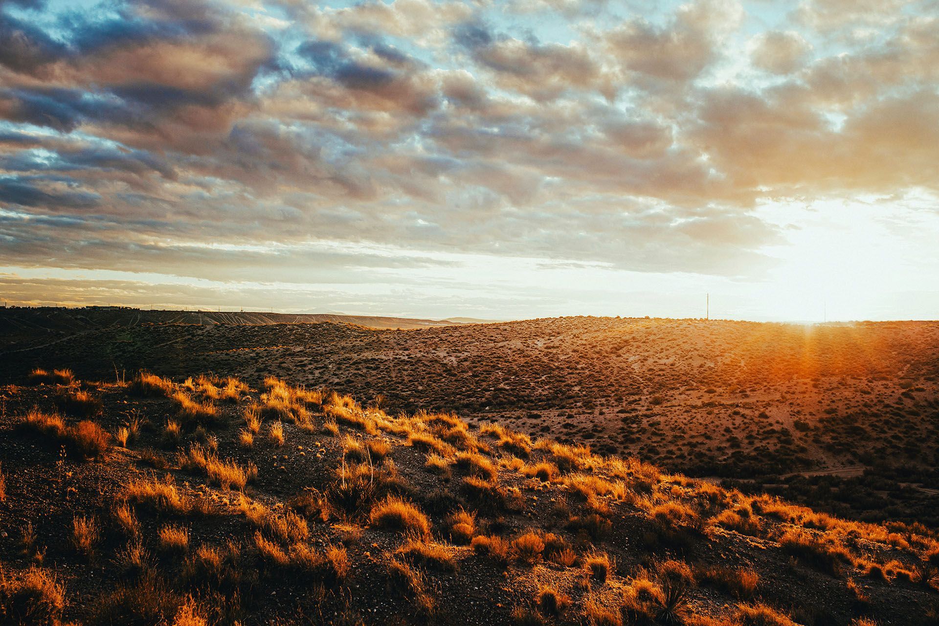 the sun is setting over a desert landscape with a cloudy sky .