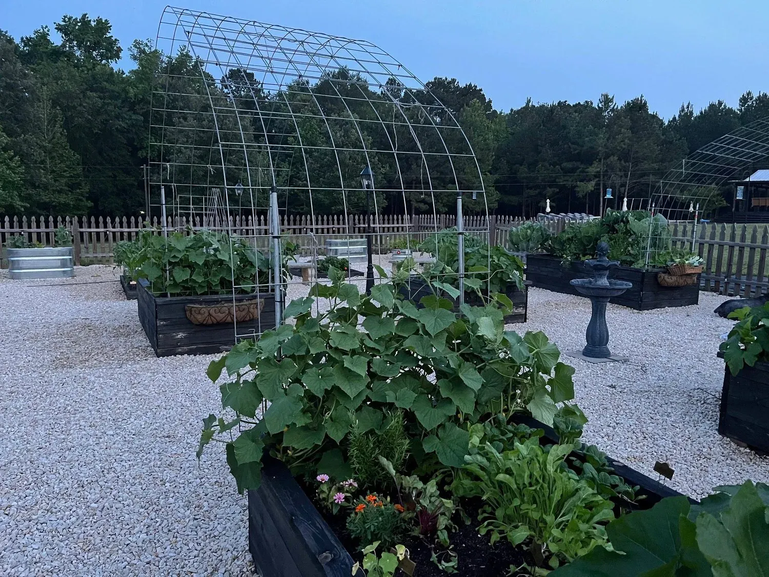 Outdoor patio with fire pit, orange sofas, and a building with arched doorway at dusk.