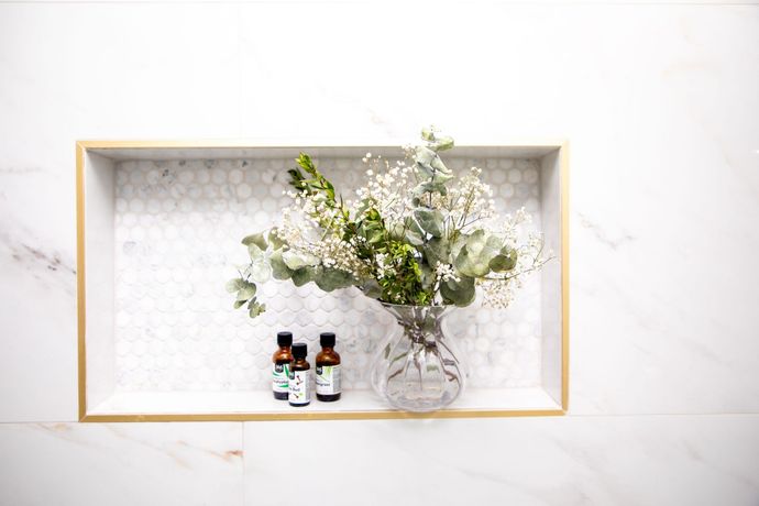 Black shed with bench and potted plants. Gravel ground, two rain barrels, and two sconces.