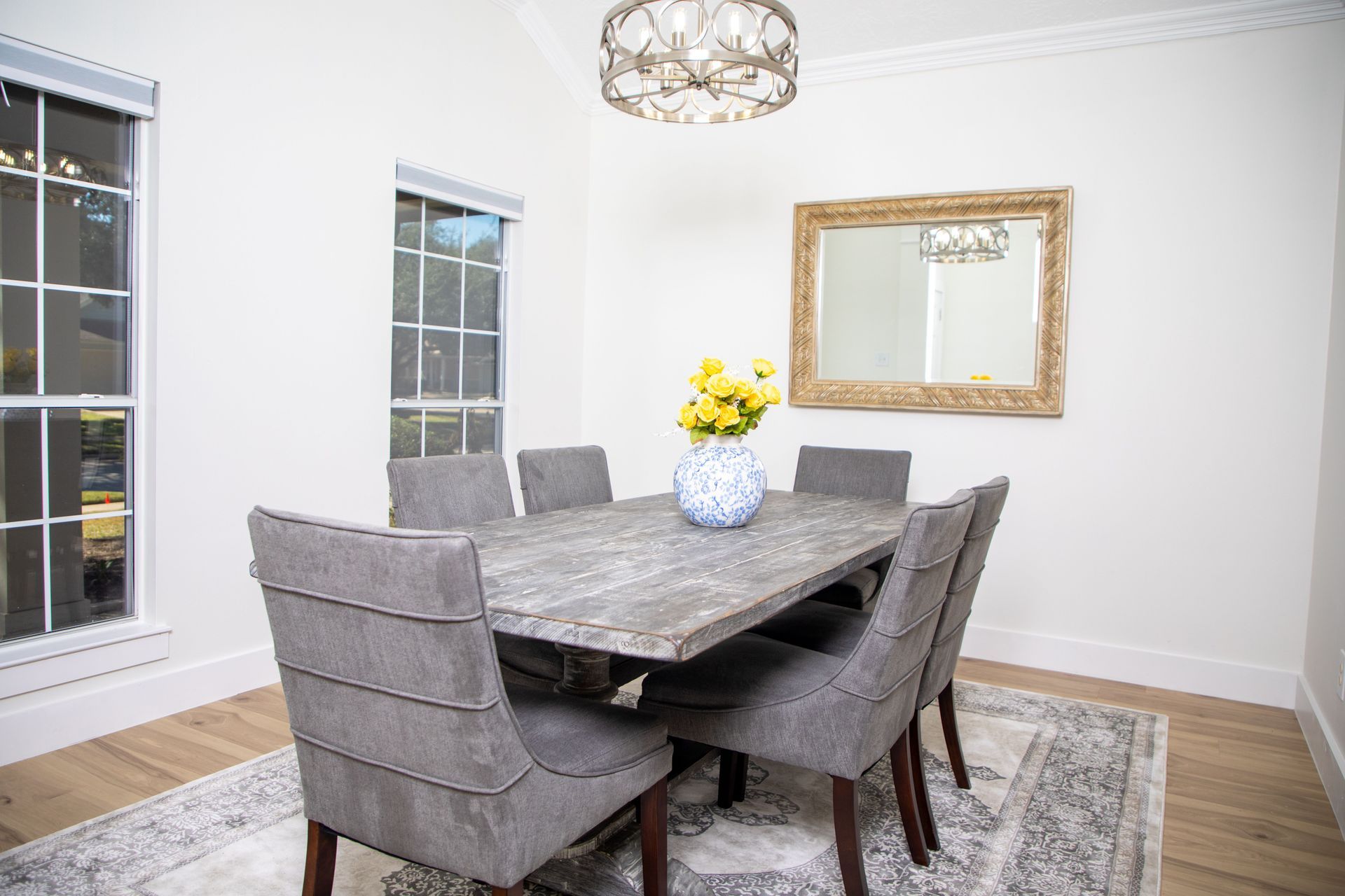 Bright dining room with a black table, white chairs, and large windows.