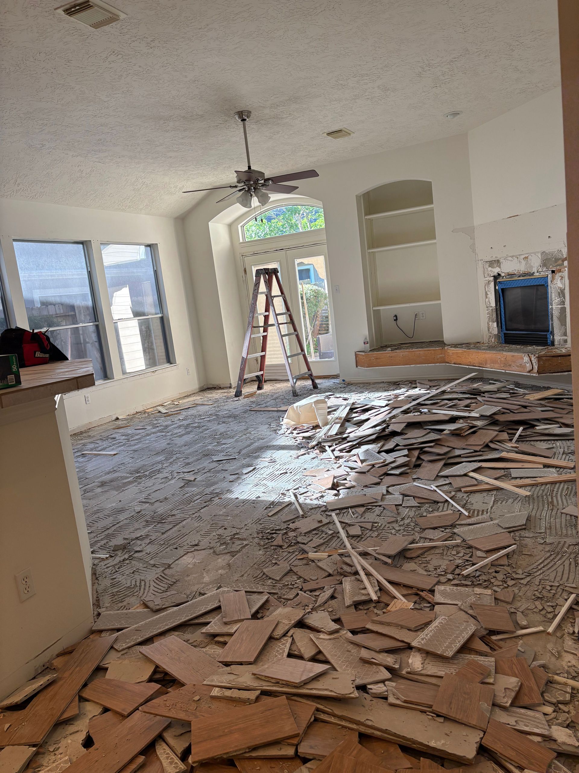 An empty, dilapidated room with peeling paint, open doors, and damaged floorboards.