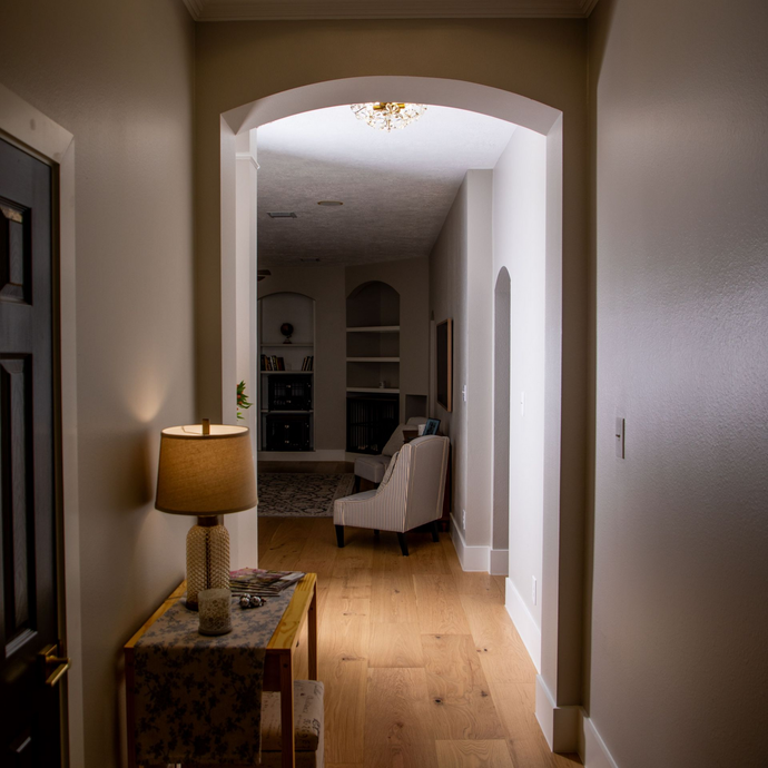 Living room with fireplace, arched windows, white sofa, two chairs, and wooden beams.
