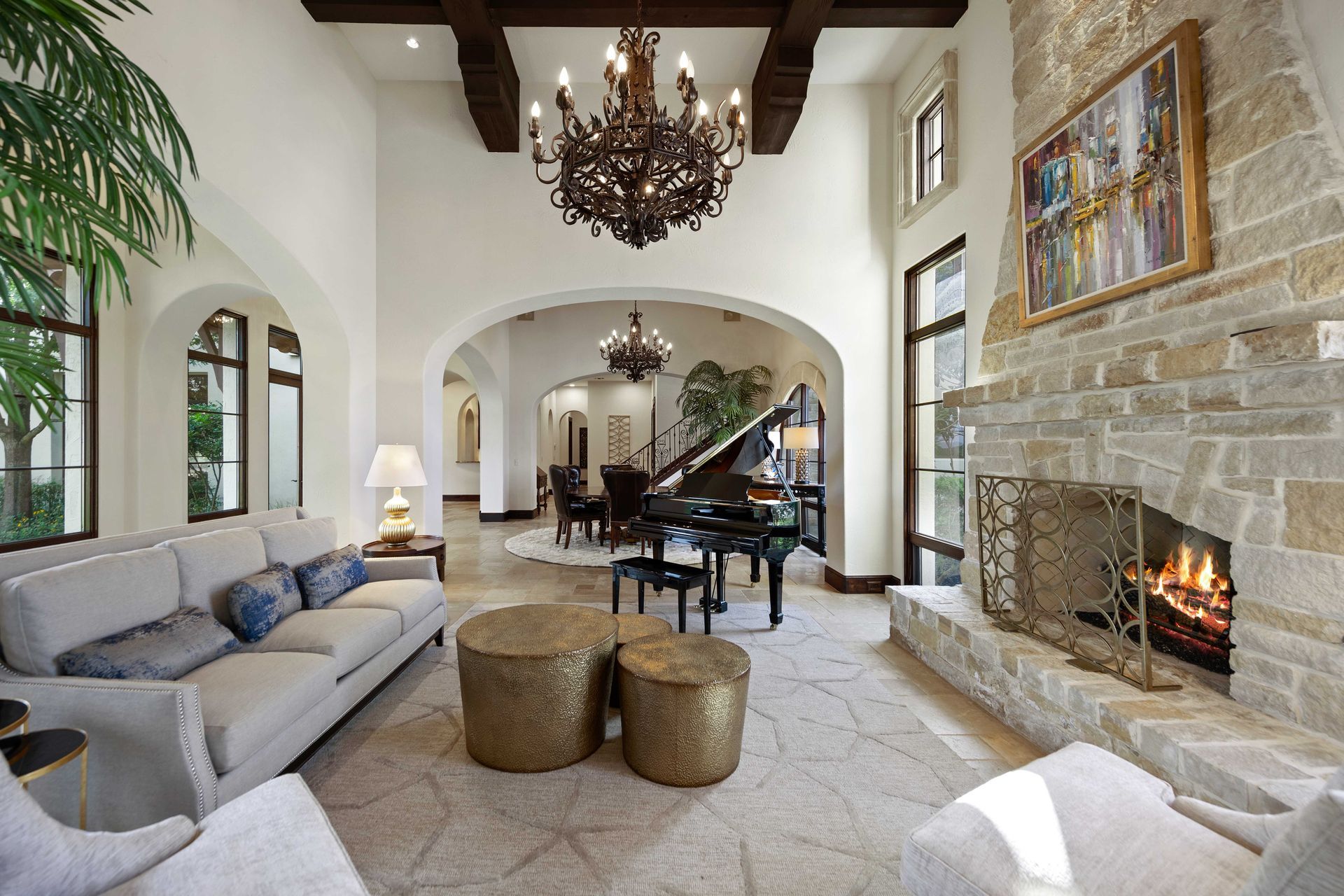 Luxurious living room with fireplace, piano, and chandelier.