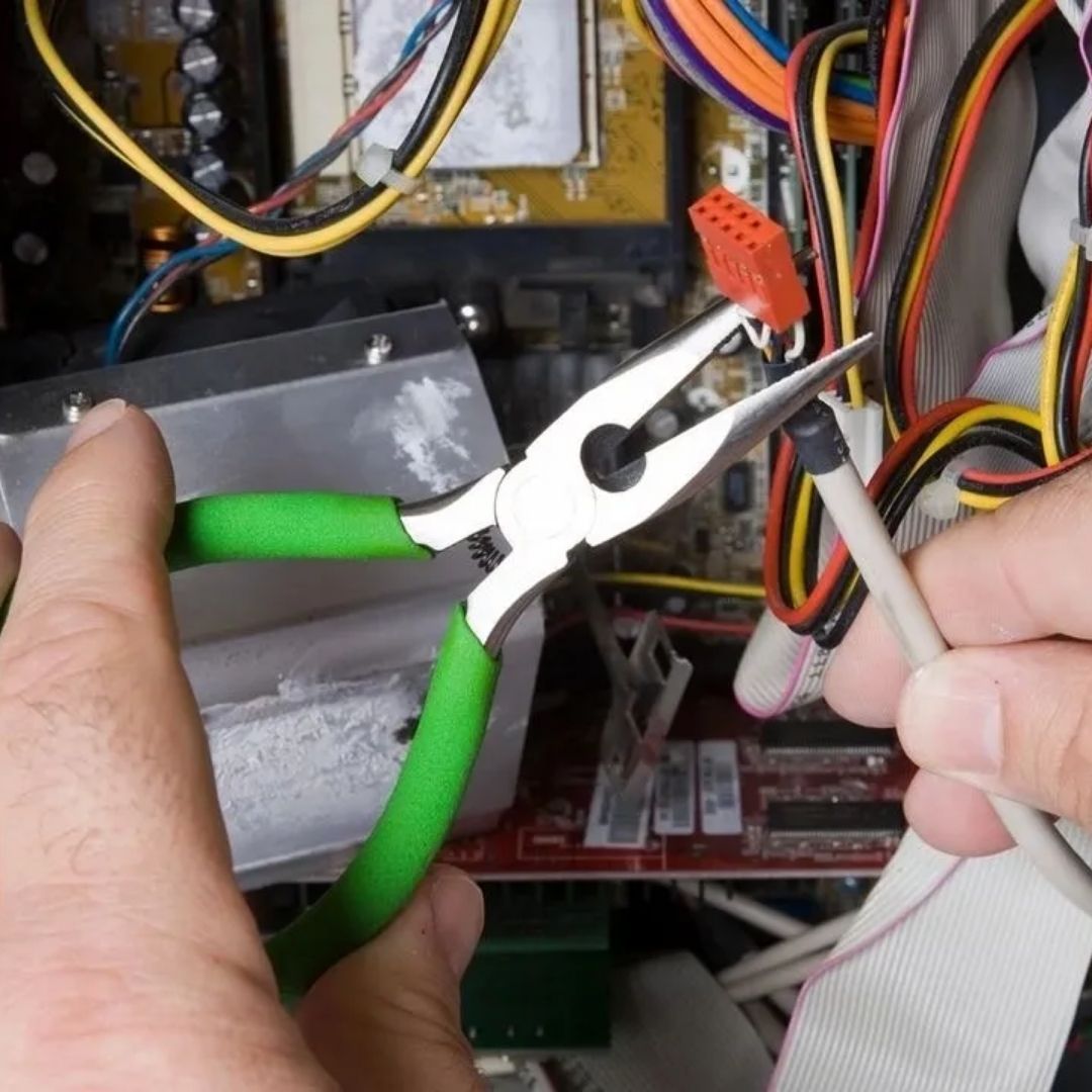 Hands using needle-nose pliers to hold a small orange electrical connector inside a computer case.