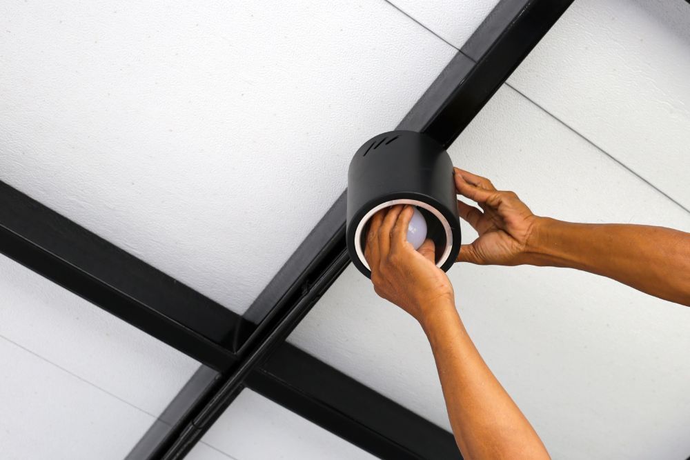 Electrician installing light fixture during emergency repair