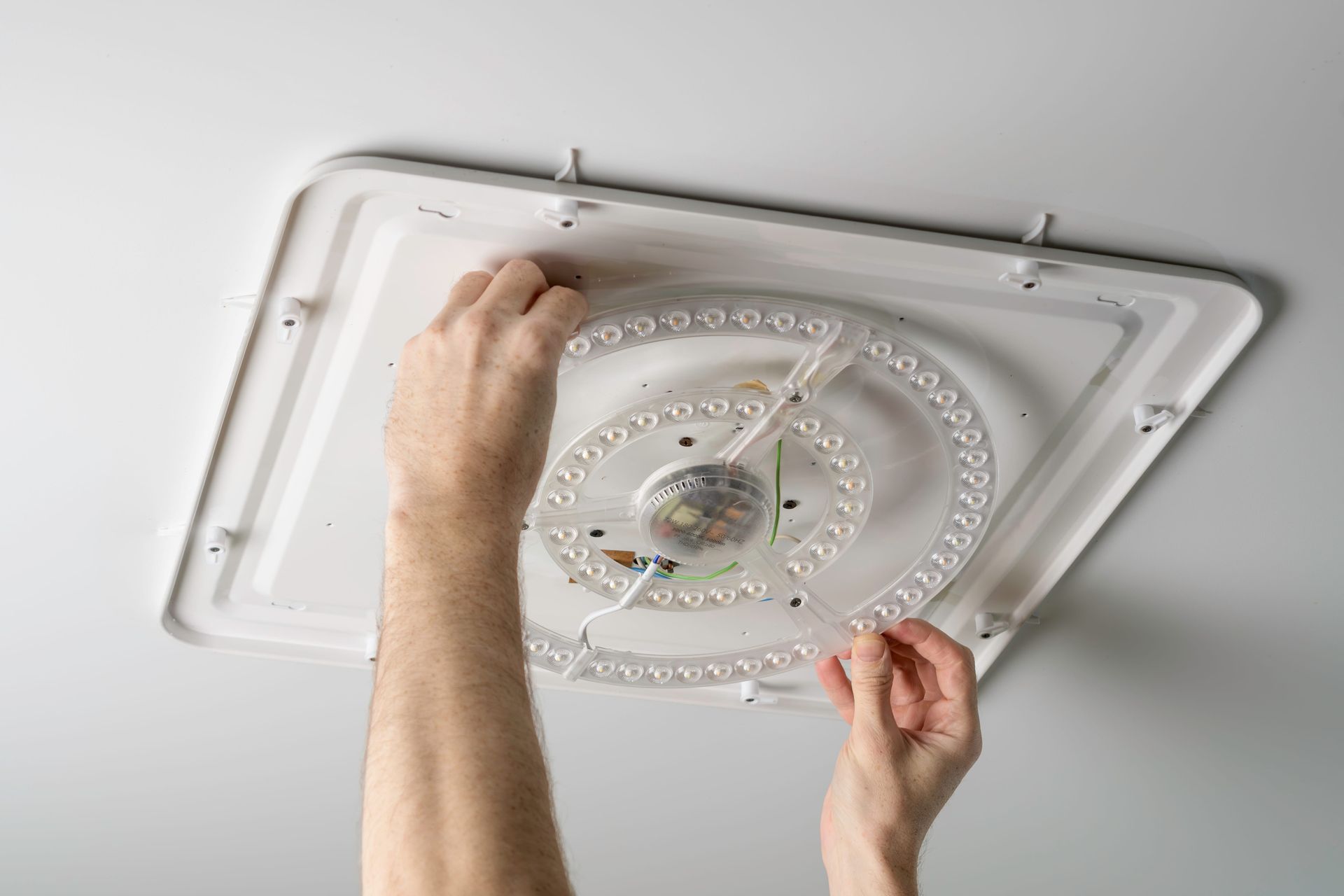 Electrician repairing an LED ceiling light fixture