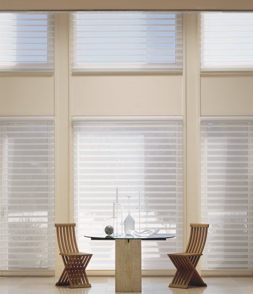 A table and chairs in front of a window with blinds