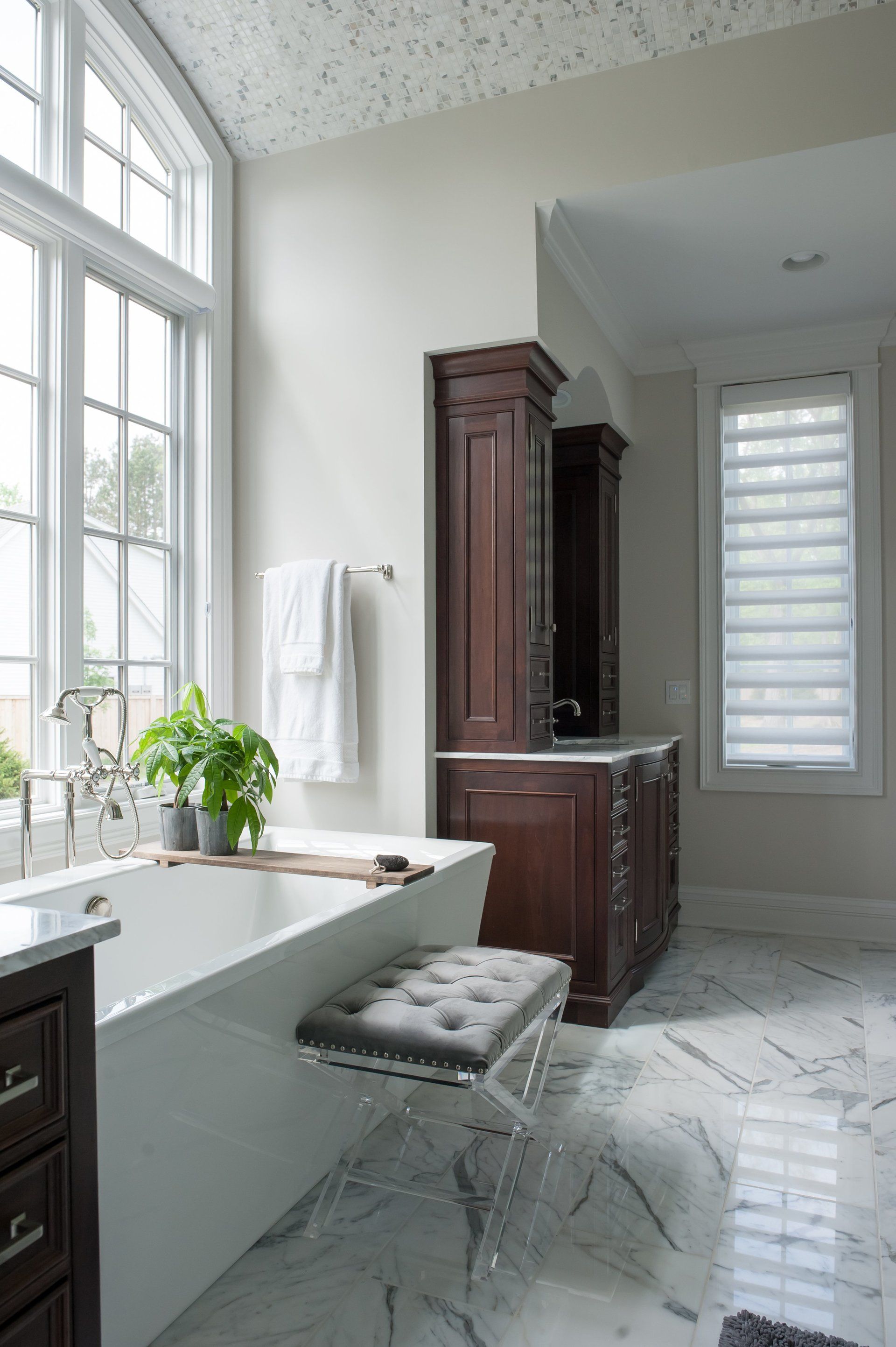 A bathroom with a tub , sink , cabinets and a window.