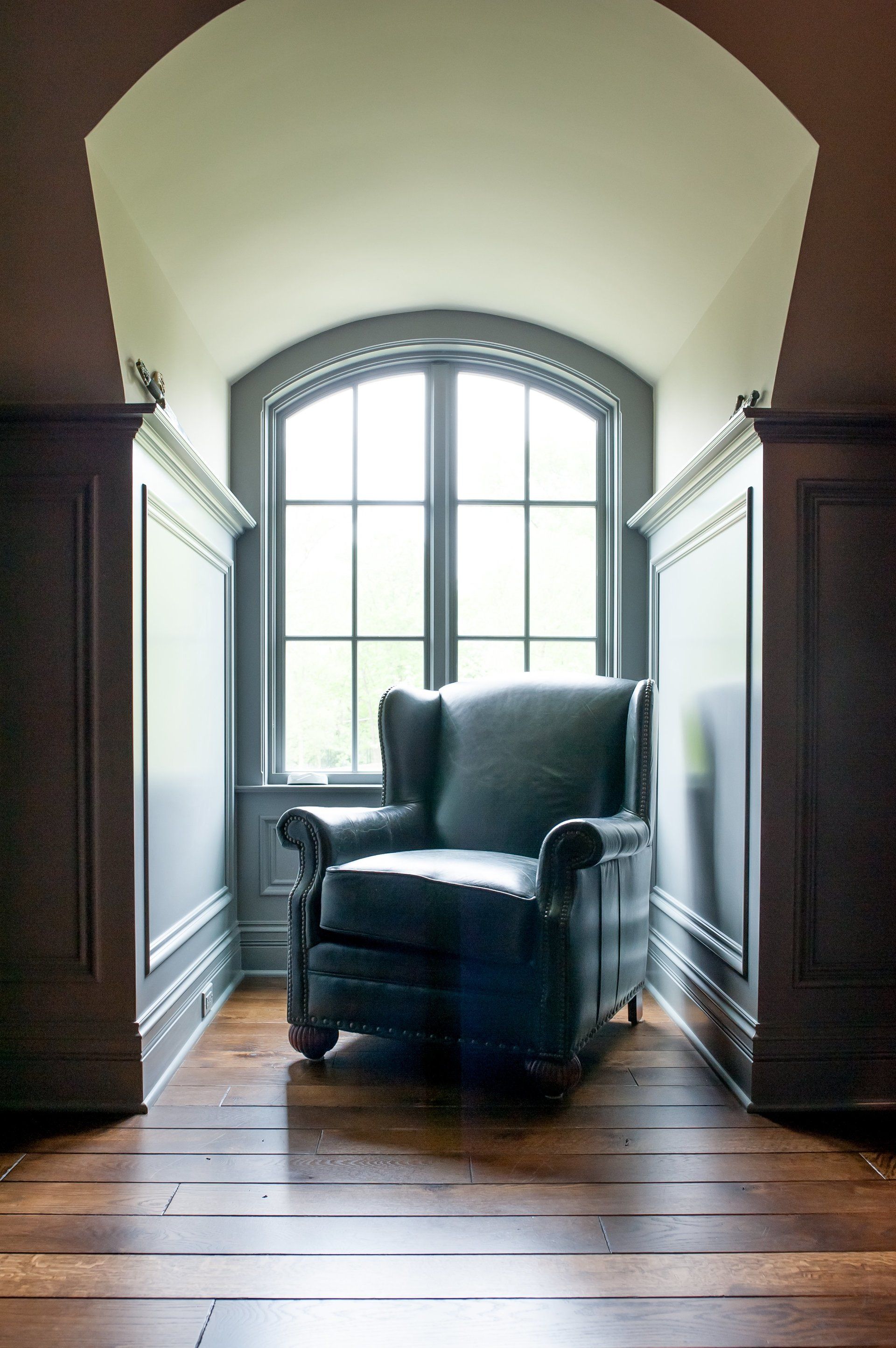 A chair is sitting in a corner of a room next to a window.