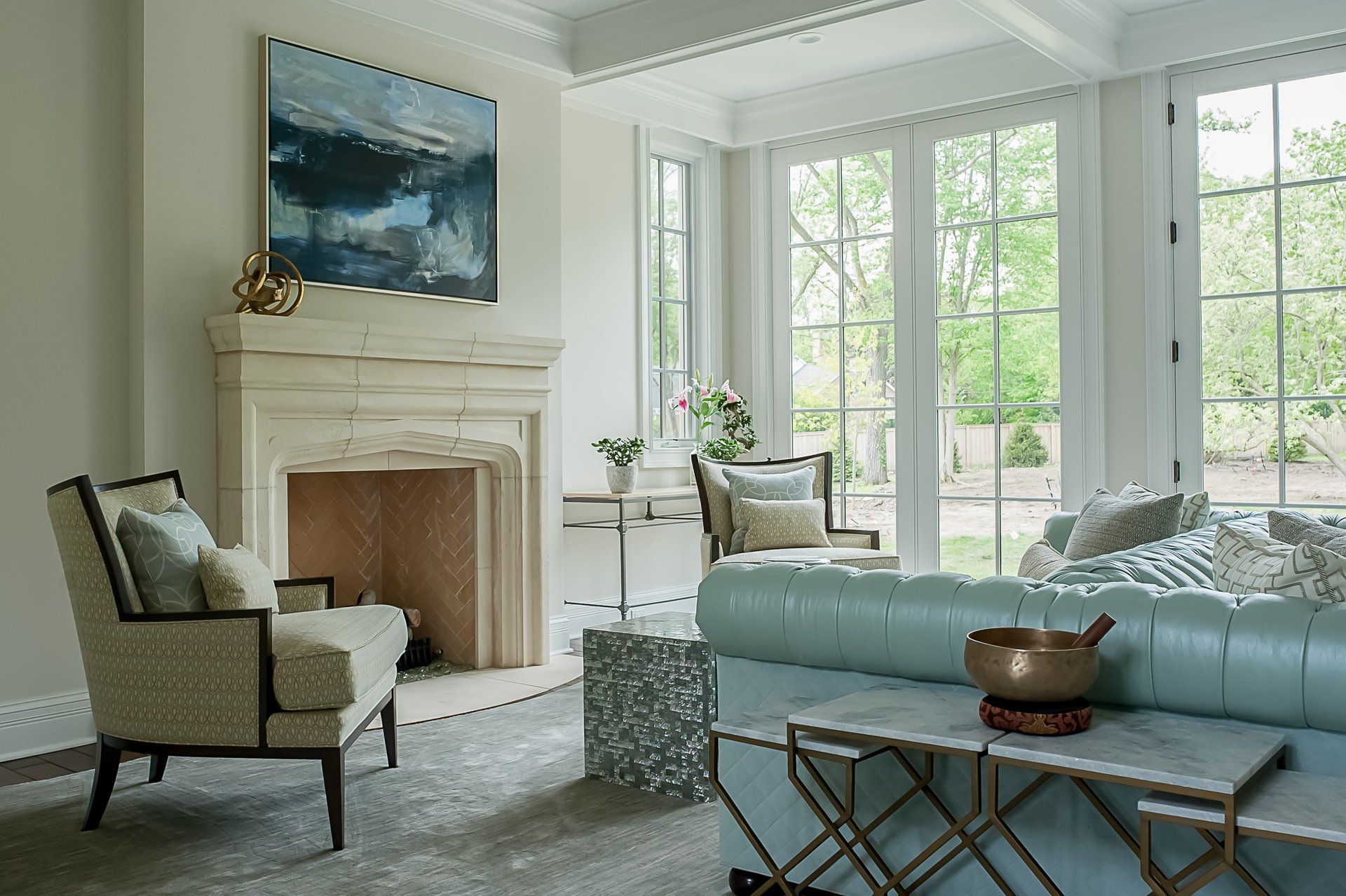 A living room with a fireplace , couch , chairs and a painting on the wall.