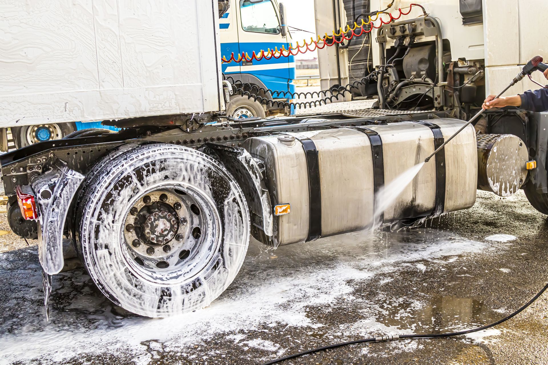 A truck being washed outdoors, with soapy water and detergents creating a foamy lather during a car wash.