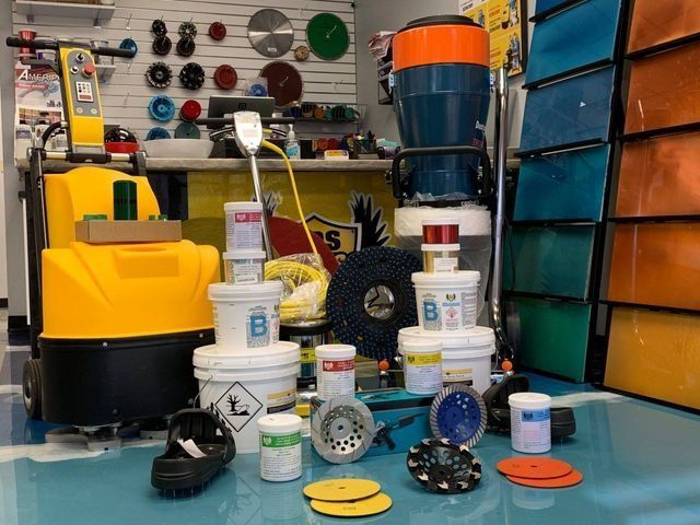Storefront displaying floor polishing machines, pads, and products. Yellow, blue, and various colors.