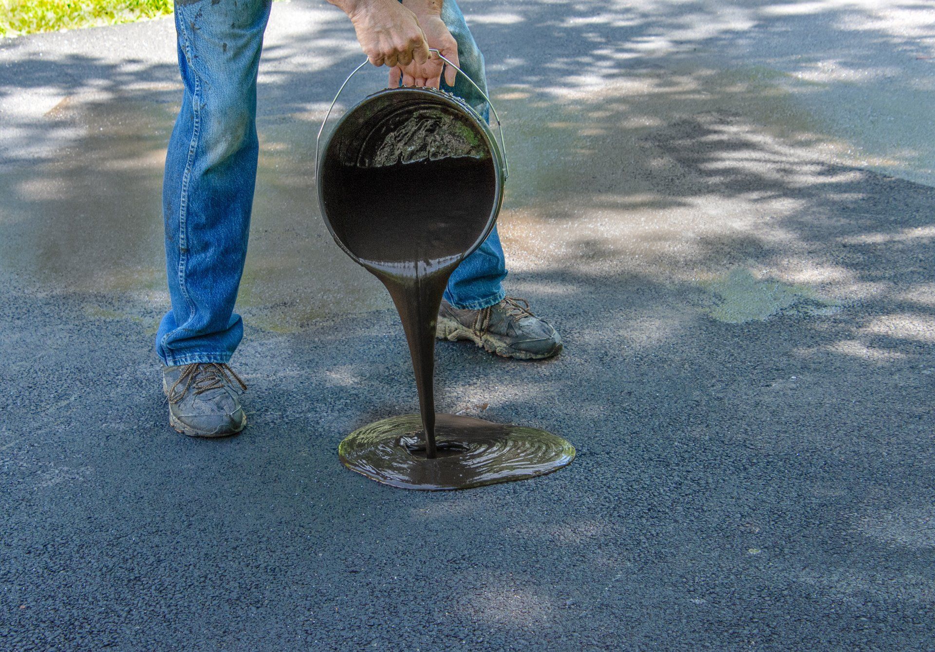 Pouring tar, asphalt sealant onto a driveway for resealing in San Antonio.