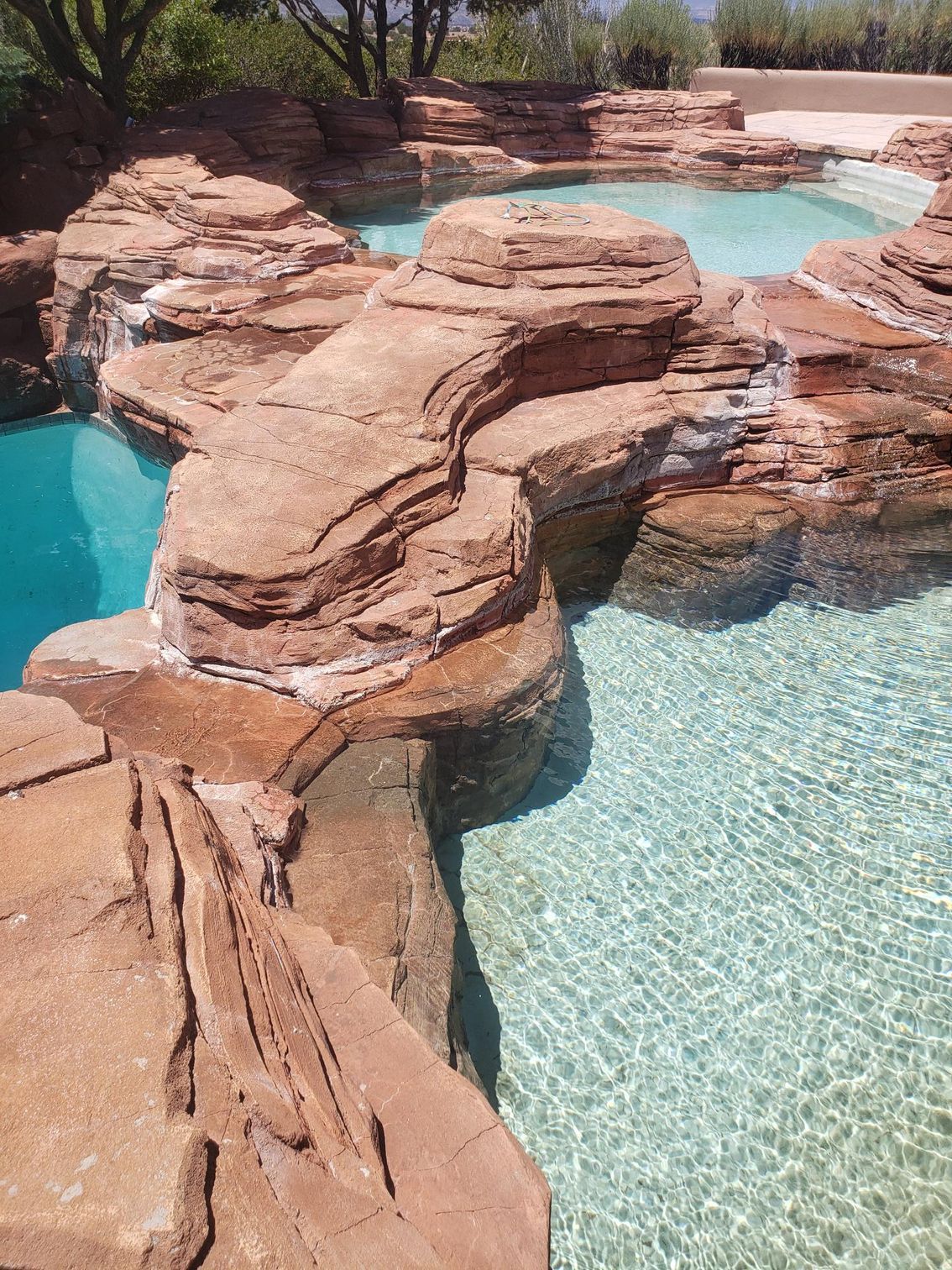 A Large Swimming Pool Surrounded by Rocks and Trees