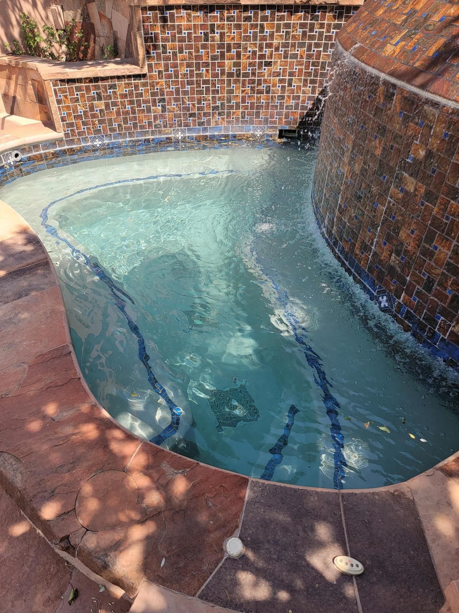 A Large Swimming Pool With a Waterfall in the Background