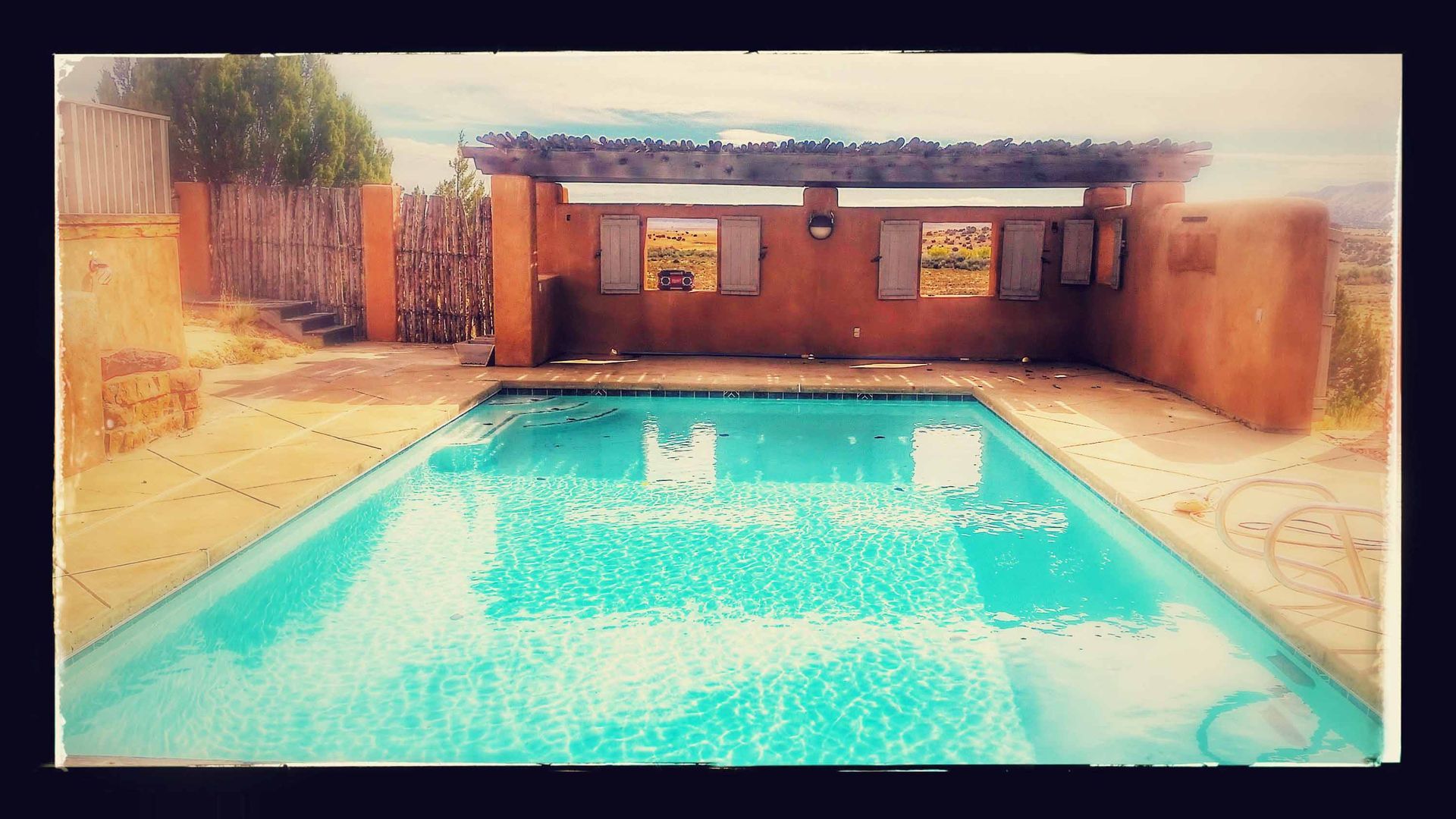 There is a large swimming pool in the backyard of a house