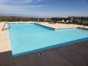 A large swimming pool surrounded by chairs and a fence