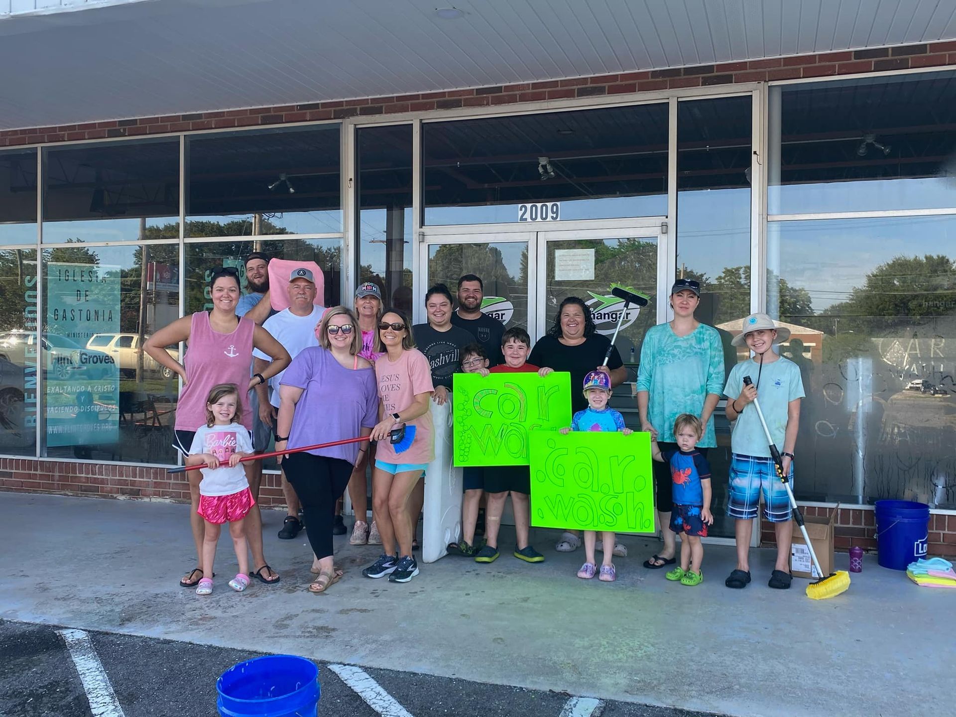Group of people with signs standing in front of a store; some holding buckets.