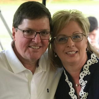 A man and a woman wearing glasses are posing for a picture