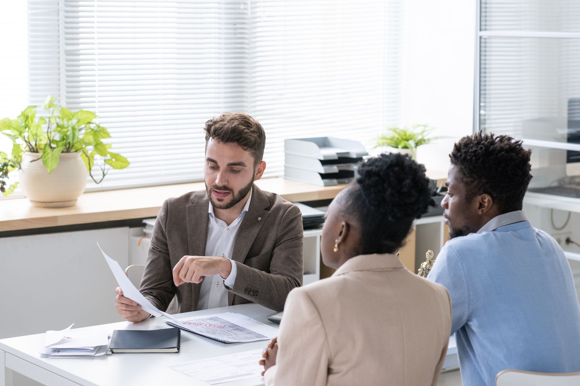 A man is sitting at a table talking to a woman and a man.