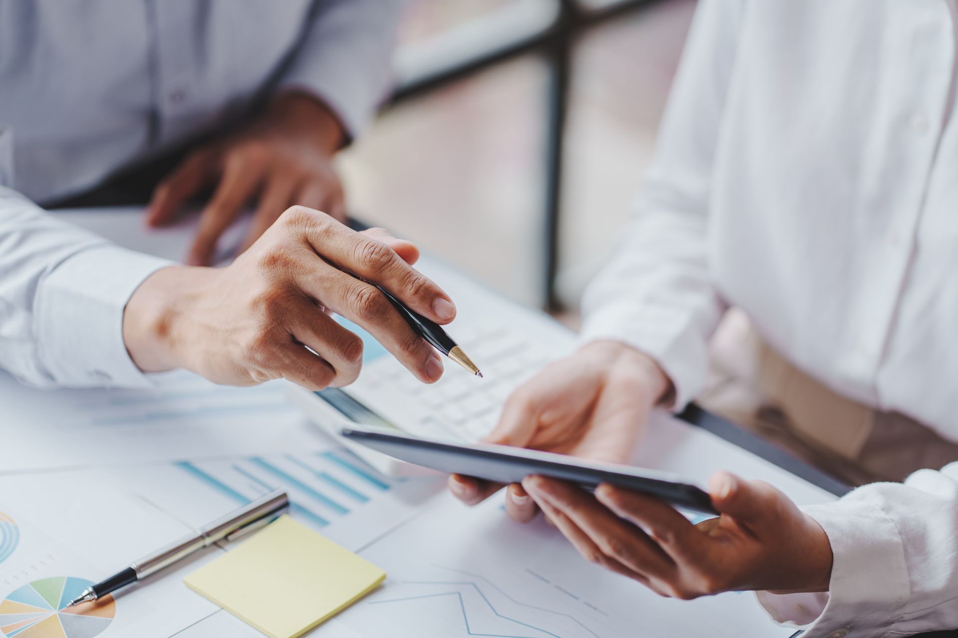 A man and a woman are sitting at a table looking at a tablet.