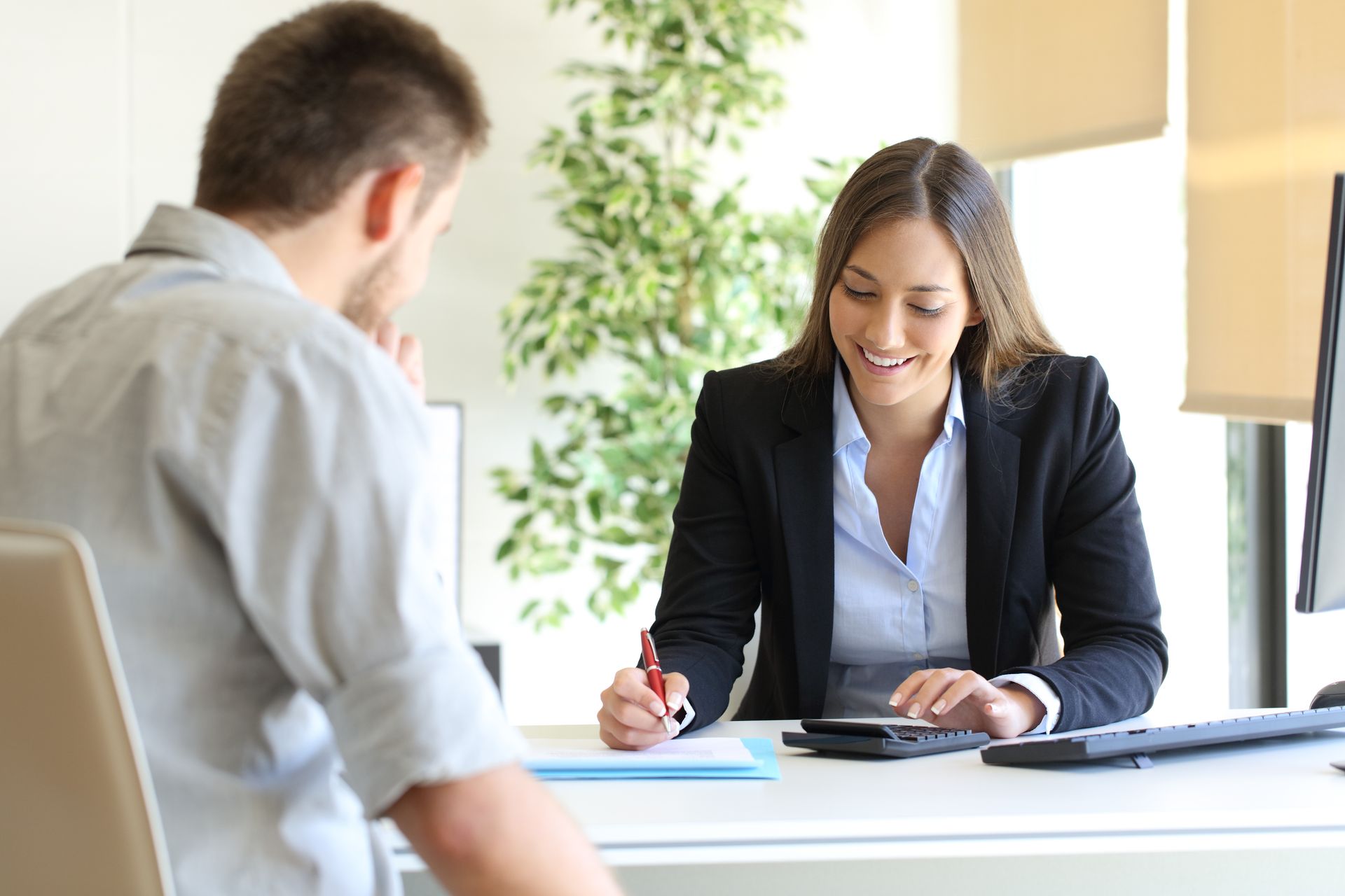 A woman is sitting at a desk talking to a man.